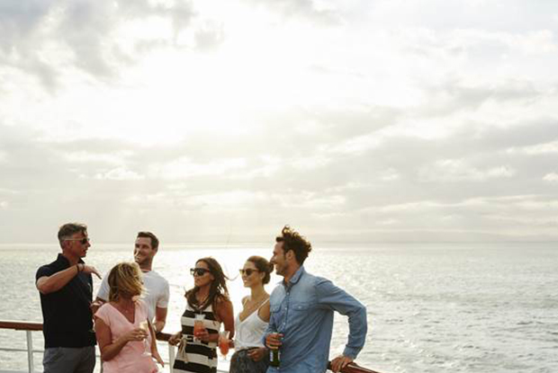 Group of people enjoying drinks on the deck at sunset